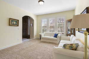 Living room with baseboards, arched walkways, and light colored carpet