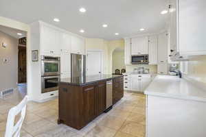 Kitchen featuring white cabinetry, visible vents, a kitchen island, and appliances with stainless steel finishes