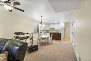 Dining area with recessed lighting, light colored carpet, baseboards, and ceiling fan with notable chandelier