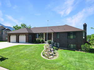 View of front of home featuring an attached garage, a chimney, a front yard, and driveway