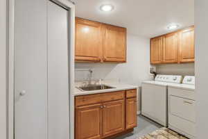 Washroom with a sink, washing machine and dryer, and cabinet space