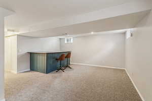 Bar with a dry bar, carpet, and baseboards