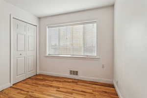 Unfurnished bedroom featuring light wood-type flooring, a closet, visible vents, and baseboards