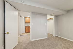 Finished below grade area featuring baseboards, visible vents, a sink, and light colored carpet