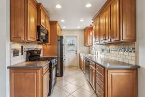 Kitchen with light tile patterned floors, brown cabinets, black appliances, a sink, and recessed lighting