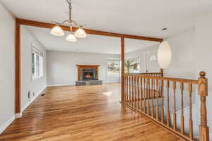 Interior space with plenty of natural light, beam ceiling, wood finished floors, and a lit fireplace