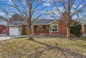 Single story home featuring a front yard, brick siding, driveway, and an attached garage