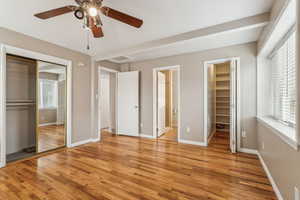 Unfurnished bedroom with ceiling fan, baseboards, a spacious closet, a closet, and light wood finished floors