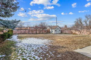 View of yard with a fenced backyard, an outdoor structure, and a storage unit