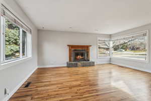 Unfurnished living room with light wood-type flooring, baseboards, a fireplace, and visible vents