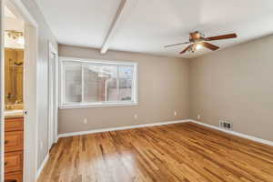 Spare room featuring visible vents, a ceiling fan, light wood-type flooring, beamed ceiling, and baseboards