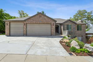 View of front of house featuring brick siding, an attached garage, concrete driveway, and a chimney