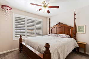 Bedroom featuring dark carpet, a ceiling fan, and baseboards