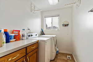 Washroom with cabinet space, visible vents, baseboards, and separate washer and dryer