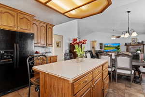 Kitchen featuring open floor plan, light countertops, black fridge, and a kitchen island