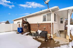 Snow covered property featuring fence and brick siding