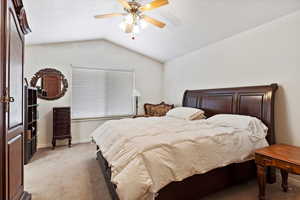 Bedroom featuring a ceiling fan, lofted ceiling, light colored carpet, and baseboards