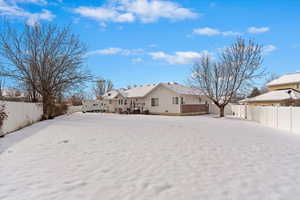 Snow covered rear of property featuring a fenced backyard