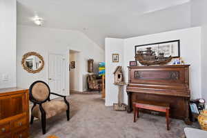 Living area with lofted ceiling, baseboards, and light colored carpet