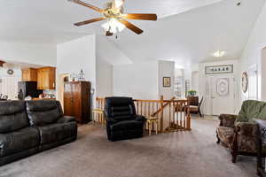 Living area featuring light carpet, ceiling fan, and lofted ceiling