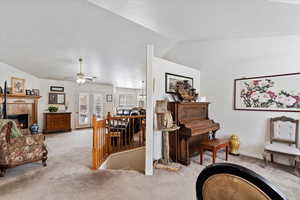 Sitting room featuring light carpet, baseboards, a ceiling fan, vaulted ceiling, and a fireplace