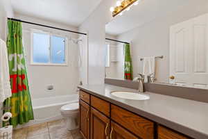 Full bathroom featuring toilet, tile patterned flooring, shower / bath combination with curtain, and vanity