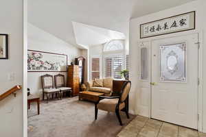 Entryway with vaulted ceiling, light tile patterned floors, and light carpet