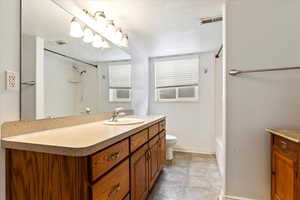 Full bathroom featuring baseboards, visible vents, vanity, and toilet