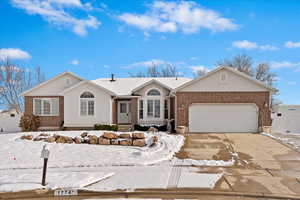 Single story home with concrete driveway, brick siding, an attached garage, and stucco siding