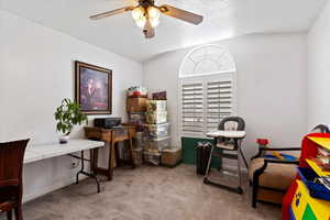 Office with light carpet, ceiling fan, baseboards, and a textured ceiling