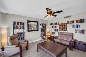 Living area featuring a ceiling fan, baseboards, visible vents, and light wood finished floors