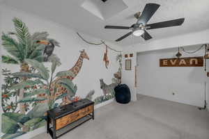 Interior space with a textured ceiling, carpet flooring, a ceiling fan, and baseboards