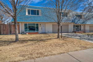 View of front facade featuring a garage, fence, mansard roof, and concrete driveway