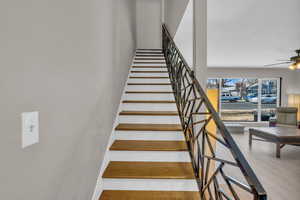 Stairs with ceiling fan, baseboards, and wood finished floors