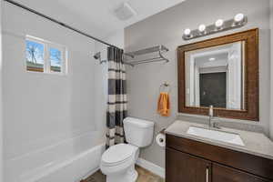 Full bath with shower / bath combo, baseboards, visible vents, toilet, and vanity