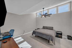 Bedroom featuring baseboards, a ceiling fan, carpet, vaulted ceiling, and a textured ceiling