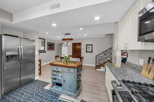 Kitchen with baseboards, visible vents, white cabinets, appliances with stainless steel finishes, and light stone counters