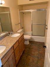 Full bathroom with double vanity, combined bath / shower with glass door, and a sink