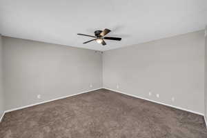 Unfurnished room with dark carpet, a textured ceiling, and baseboards