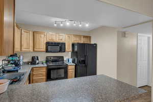 Kitchen featuring wood finished floors, a sink, light countertops, light brown cabinetry, and black appliances