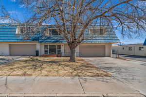 Townhome / multi-family property with a garage, concrete driveway, brick siding, and mansard roof