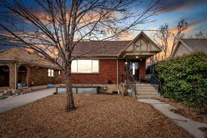 View of front of house featuring a shingled roof, covered porch, and brick siding