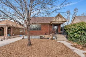 View of front of house with a shingled roof and brick siding