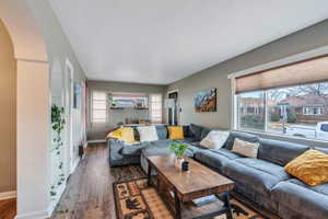 Living room featuring arched walkways, dark wood-style flooring, and baseboards