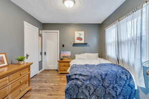 Bedroom with light wood-style floors and a textured ceiling