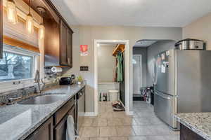 Kitchen featuring appliances with stainless steel finishes, pendant lighting, a sink, and light stone countertops