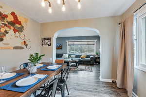 Dining space featuring dark wood-style floors, arched walkways, and baseboards