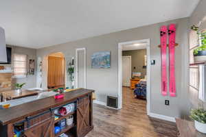 Interior space featuring baseboards, visible vents, arched walkways, and wood finished floors