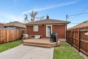 Back of property featuring brick siding, a fenced backyard, a patio, and a wooden deck