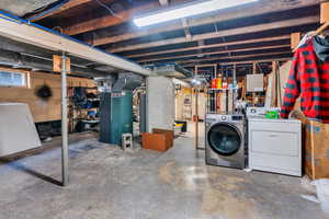 Basement featuring heating unit, water heater, and washer and clothes dryer